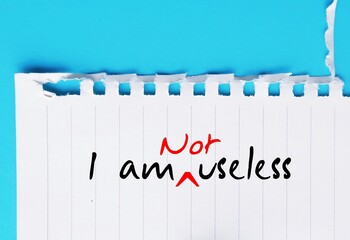 Torn paper with handwritten text I AM USELESS changed to I AM NOT USELESS -  Challenge negative...
