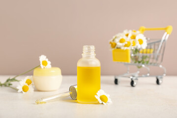 Composition with chamomile flowers, bottle and jar of cosmetic products on beige background, closeup