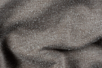 Macro texture of gray fabric with lots of pilling and damage on the surface.