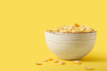 Bowl of tasty cornflakes on yellow background