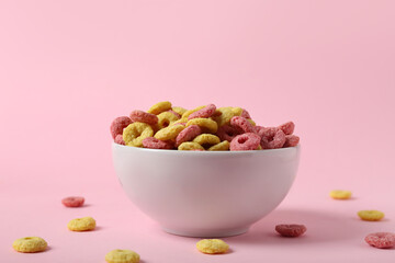 Bowl of tasty cereal rings on pink background