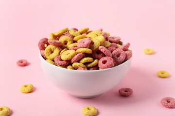 Bowl of tasty cereal rings on pink background