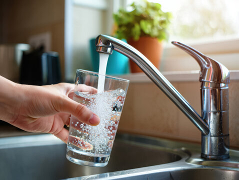 Filling a glass with fresh tap water in a kitchen