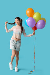Beautiful teenage girl with colorful air balloons on blue background
