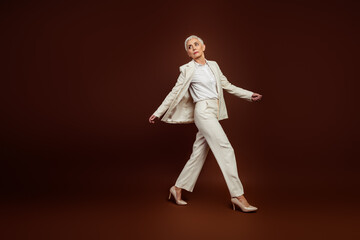Confident mature senior female model in elegant formalwear striking a graceful pose with vibrant...