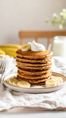 Stack of Banana Oat Pancakes with Whipped Cream on Rustic Linen
