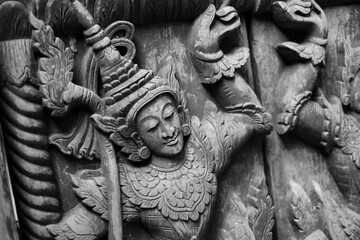 Black and white image. A carved wooden door with Thai deity motifs is commonly found in Thai temples.