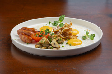 A delicious brunch breakfast platter showcases sunny-side-up eggs, sausages, mushrooms, and grilled tomato on a white plate, perfect for morning energy.