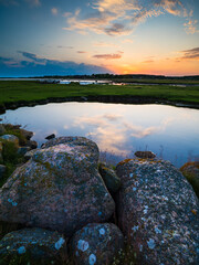 Tranquil sunset over a nature reserve coastline in Sweden with reflective water and rocky landscape