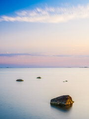 Coastal scenery at dusk in Sweden showcasing smooth waters and distant rocks under a pastel sky