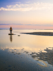 Man standing on stone at the sea during a picturesque sunset in Sweden