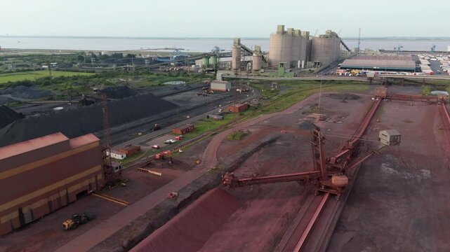 Aerial drone shot raw material coal iron ore mining equipment stacker Reclaimer Machines, Dump Trucks, And Stockpile Of Iron Ore At The Coal Handling Area Immingham England UK