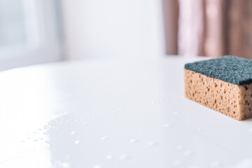 Household sponge resting on a wet surface in natural light, emphasizing cleanliness and routine care. High quality photo