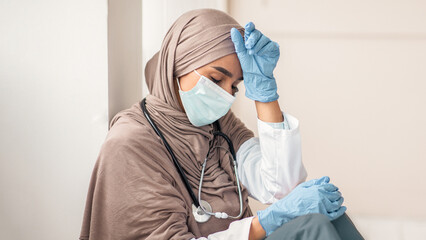 Upset woman in hijab doctor having difficult day at clinic, wearing protective gloves and face...