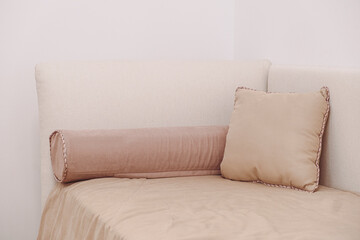 Beige sofa corner with plush and bolster pillows creates a cozy and inviting seating area. The soft...