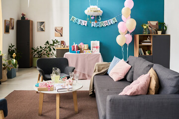 Decorated living room featuring pastel balloons, gift boxes, and baby shower banner arranged for...