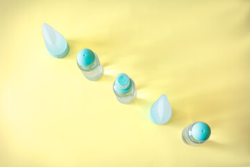 Symmetrical composition of plastic cosmetic bottles and travel toiletry containers on a pastel yellow background. Simple, fresh beauty product layout with modern aesthetic