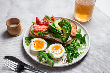  Sandwich with salmon, avocado, tomatoes and egg in a white plate on the table close-up. Healthy breakfast