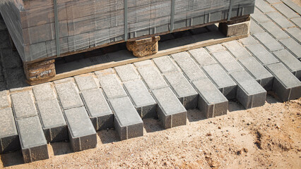 Construction site with stacked pavers and completed pavement during daylight