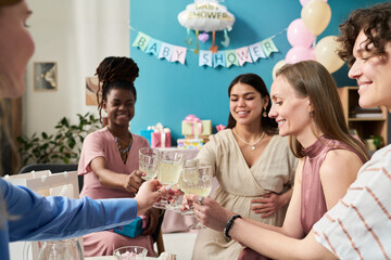 Group of young adult women including Black and Caucasian raising glasses in celebration at gender...