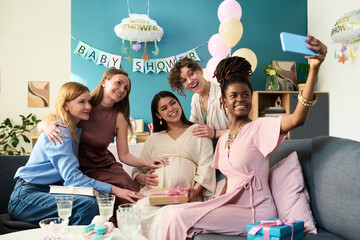 Group of young adult women including Caucasian and Black woman gathering for gender reveal party
