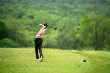 A man is swinging a golf club on a grassy field