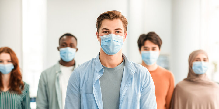 New Reality Rules, Epidemic Concept. Portrait of young man wearing protective medical mask standing with diverse group of international people in the blurred background, posing and looking at camera - Powered by Adobe