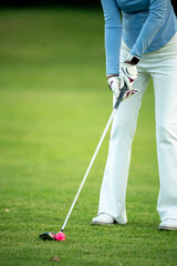Obraz premium A woman is playing golf and is about to hit the ball