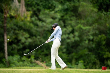 A woman is swinging a golf club