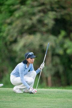 A woman is kneeling on a golf course