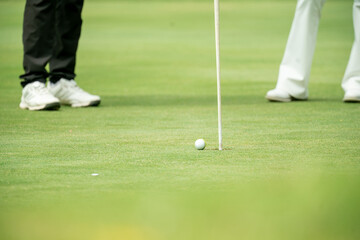 A golf ball is on the ground next to a golf club
