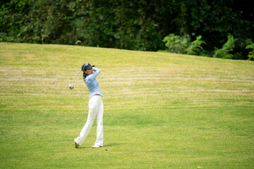 A woman is playing golf on a grassy field