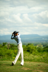 A woman is swinging a golf club