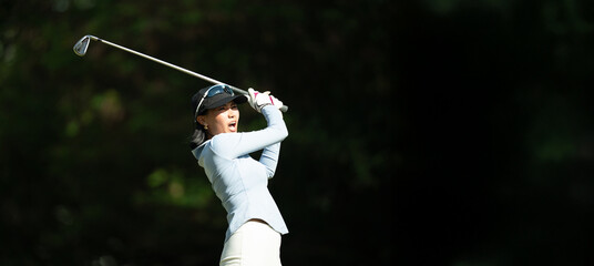 A woman is swinging a golf club