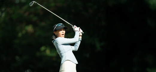 A woman is swinging a golf club