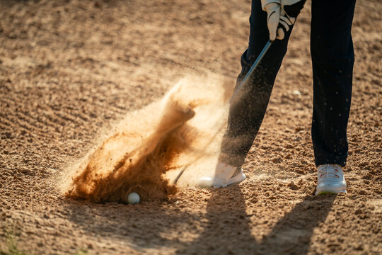 A person is swinging a golf club and the ball is in the air