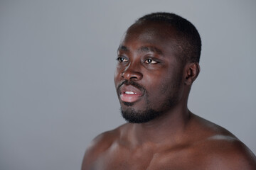 African American man with short hair and beard looking slightly away from camera against grey...