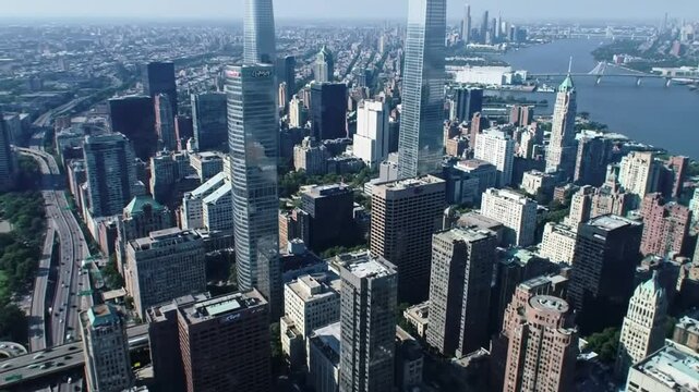 Stunning aerial footage capturing a panoramic view of a bustling metropolitan city during daytime. Features towering skyscrapers, modern architecture, and a river in the background, showcasing urban g