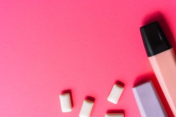 Chewing gum, a pink highlighter, and a purple eraser on a vibrant pink background. Flat lay with bold Gen Z aesthetic. High quality photo