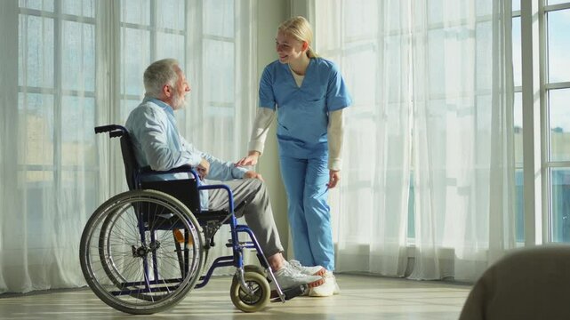 Help support retirement healthcare. Nurse helping old man in wheelchair. Patient and woman in nursing home for medical caregiver. Nurse taking care of paralyzed man in chair for people with disability