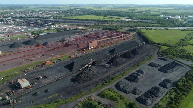 Aerial drone shot raw material coal iron ore mining equipment stacker Reclaimer Machines, Dump Trucks, And Stockpile Of Iron Ore At The Coal Handling Area Immingham England UK