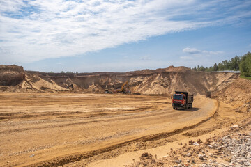 Active work in a sand quarry. Bucket trucks load sand into trucks.