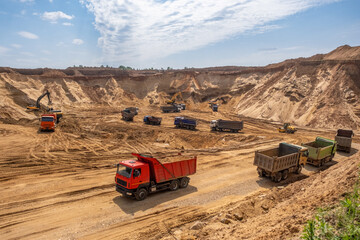 Active work in a sand quarry. Bucket trucks load sand into trucks.