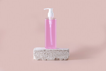 Pump bottle for cosmetics on the podium made of stone  on a pink background
