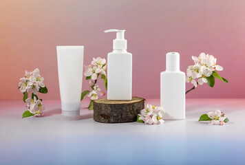 cosmetics containers on a wooden podium and branches of a blooming apple tree on a gradient background