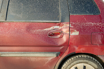 red car dented in the area of the rear door. car after an accident, impact. The rear door of the red car is damaged,