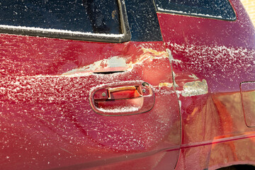 Red car door dented after accident, car hit. Impact damage. Damaged rear door of car, dent after road collision