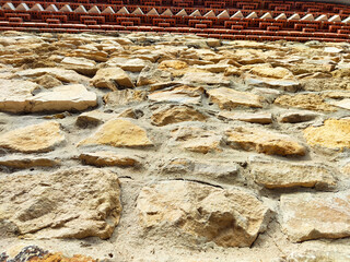 Texture of rustic stone wall with vibrant architectural details captured from a low angle,...