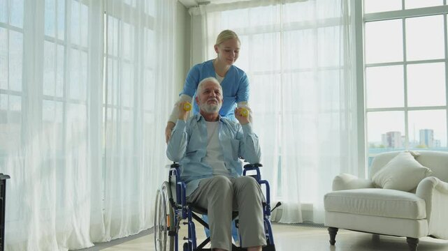 Support rehabilitation healthcare. Nurse helps old man patient in wheelchair picking up dumbbells. Paralyzed man in chair for people with disability doing sports exercise with nurse. Medical caregiver