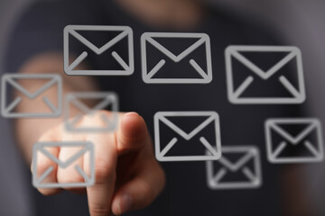 Hand pointing at email icons on a touchscreen.  Concept of communication, digital messaging, and...